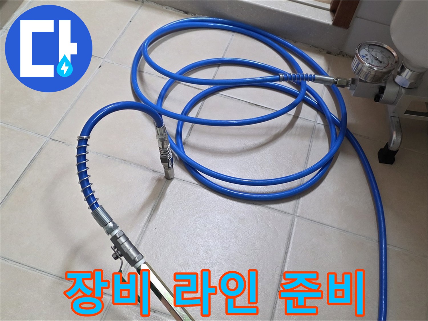 타일 바닥에 놓인 파란색 호스와 압력 측정용 밸브 장치