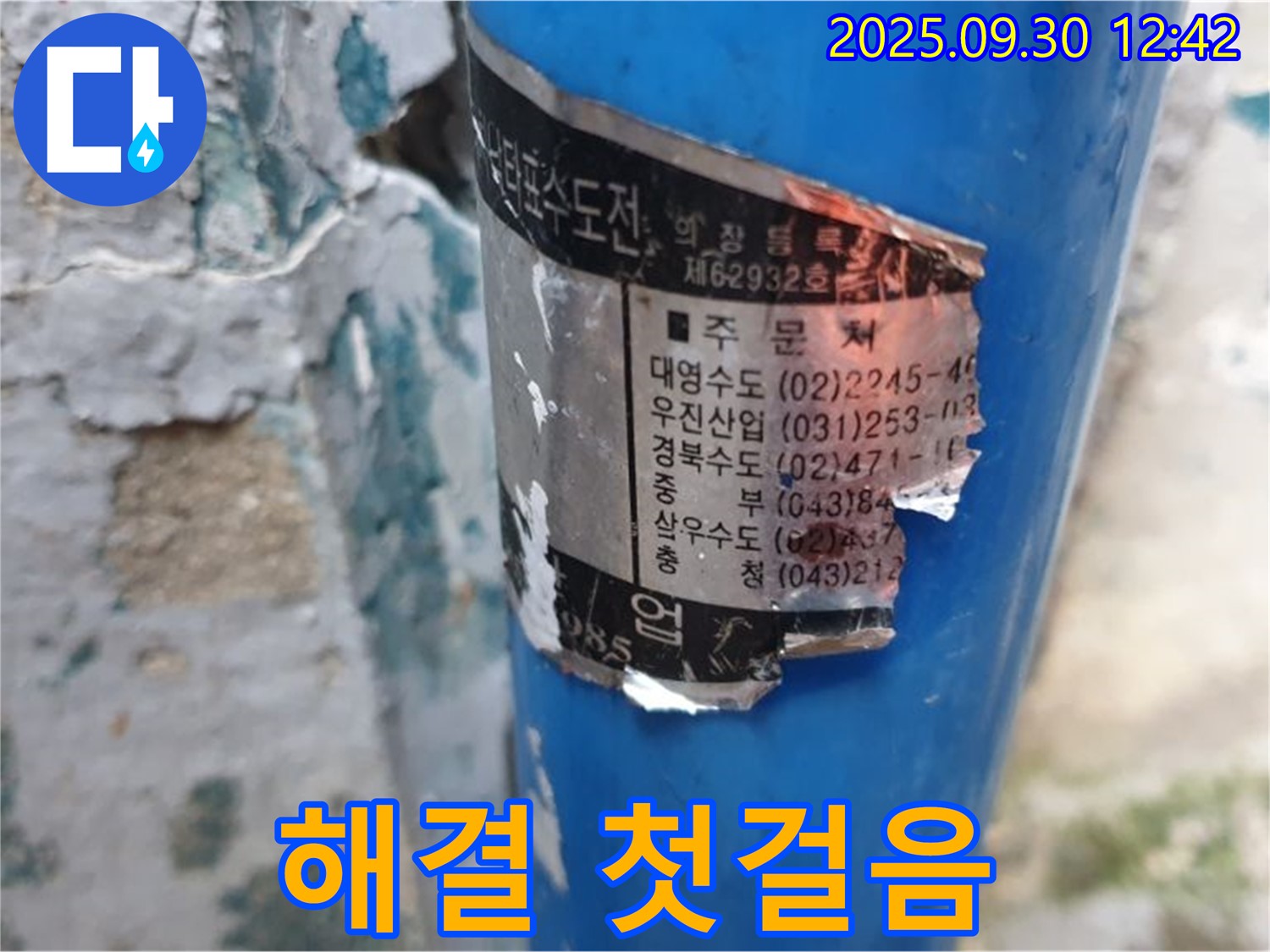 수도 배관에 부착된 오래된 스티커 - 시공 업체 정보와 다양한 연락처가 꼼꼼하게 적혀 있어 누수 해결의 첫걸음이 될 수 있습니다.