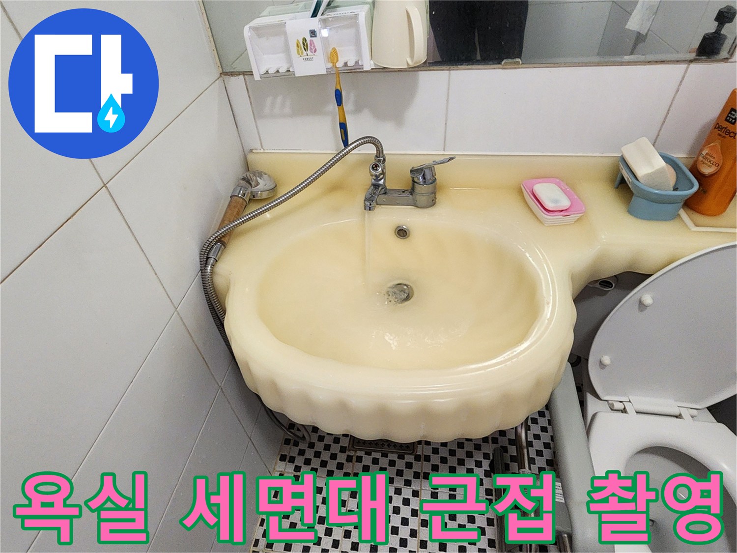 화장실 세면대 수전과 변기 주변의 타일 및 배관 연결 상태입니다.