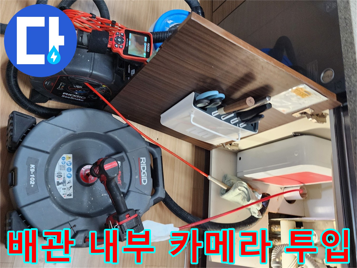싱크대 하단 배관의 균열을 찾기 위해 내시경 장비를 연결하여 작업하는 모습