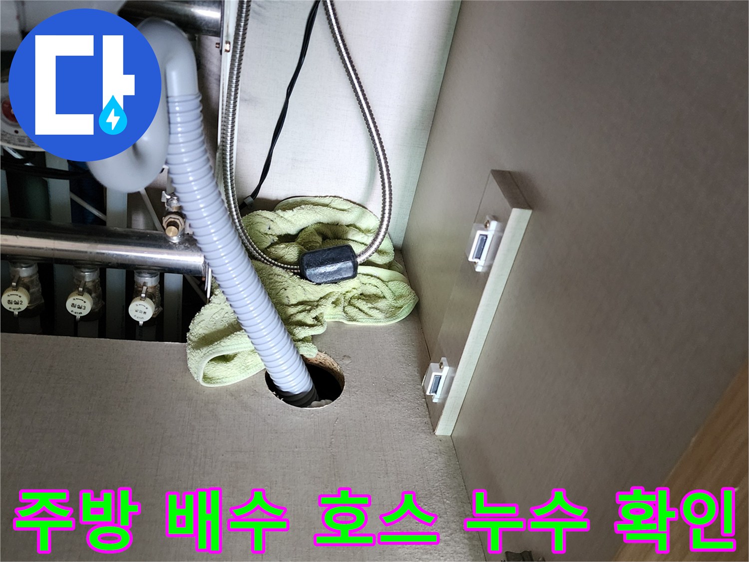 싱크대 하부 배수 호스 연결 부위와 바닥 구멍 주변의 습기 상태를 나타내는 사진입니다.