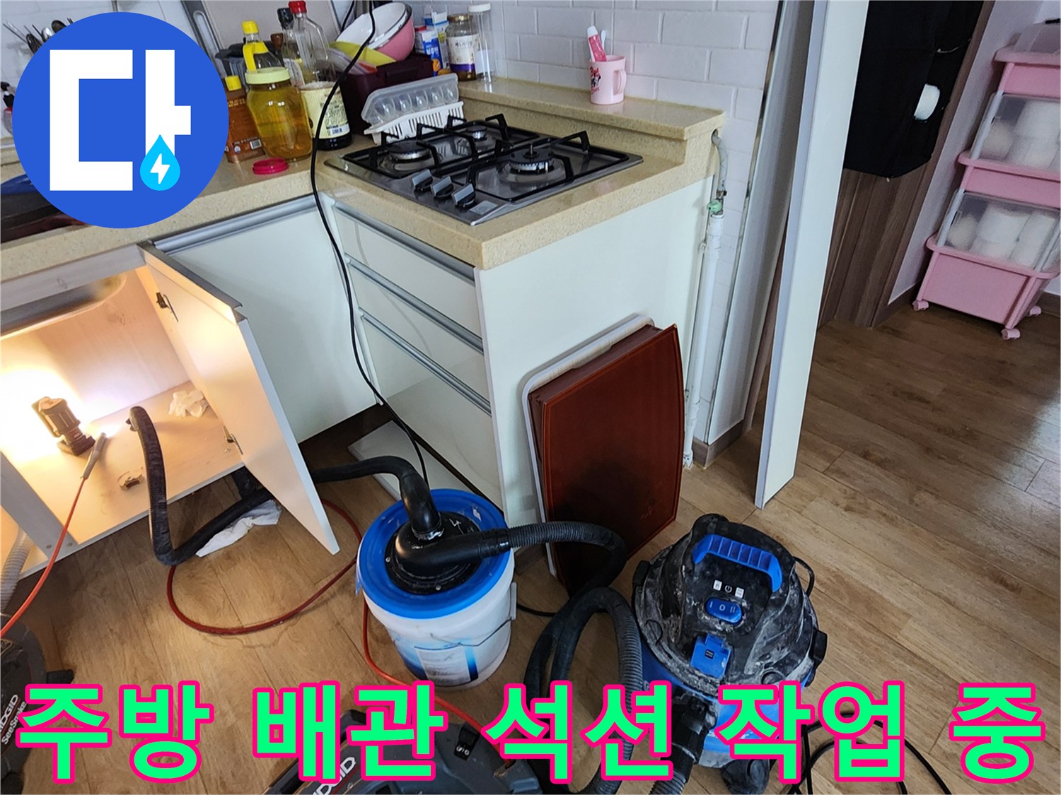 싱크대 아래쪽에서 작동 중인 산업용 습식 청소기 및 호스