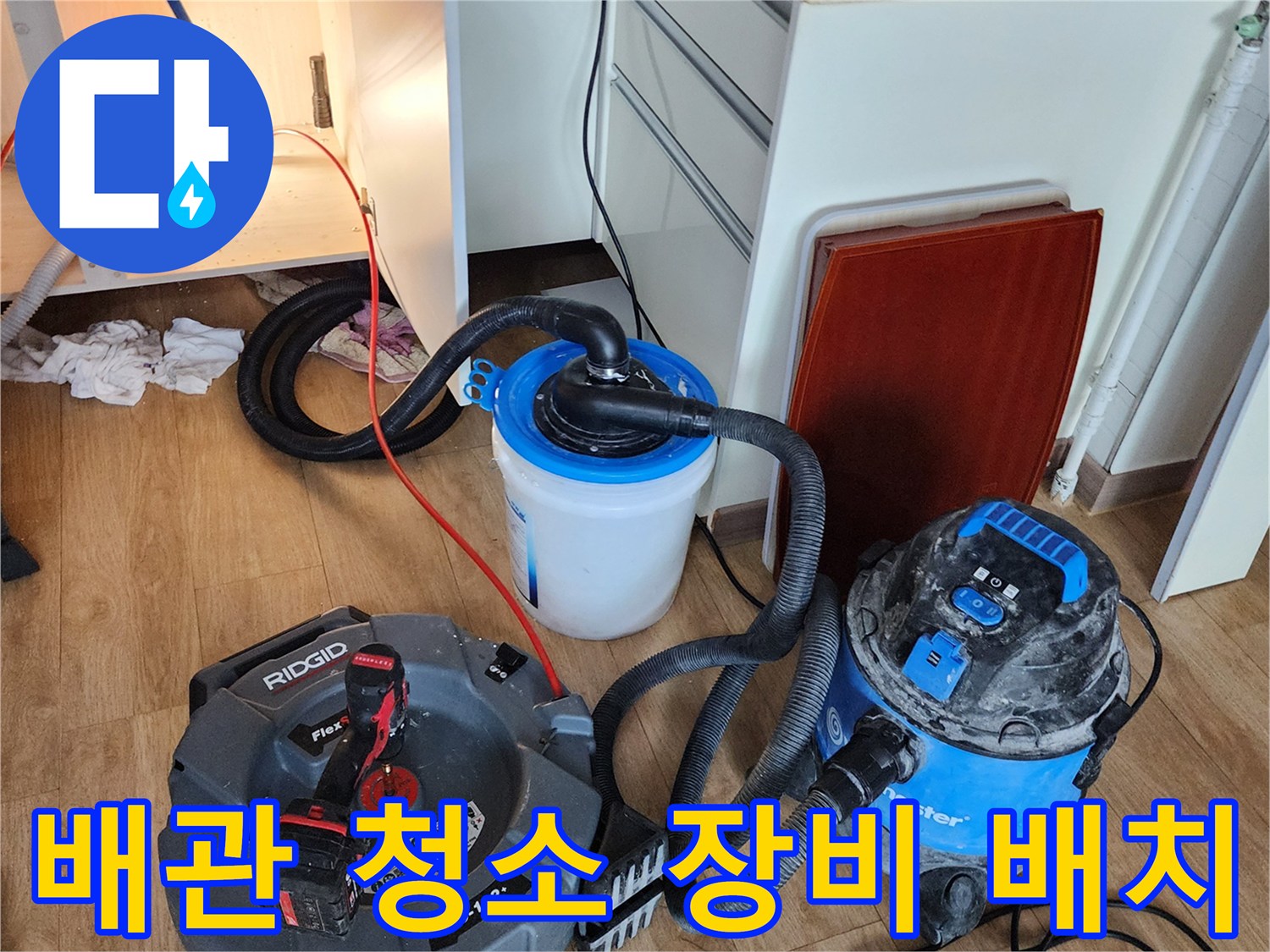 싱크대 하부장 아래 설치된 배관 세척용 석션기와 수집 용기