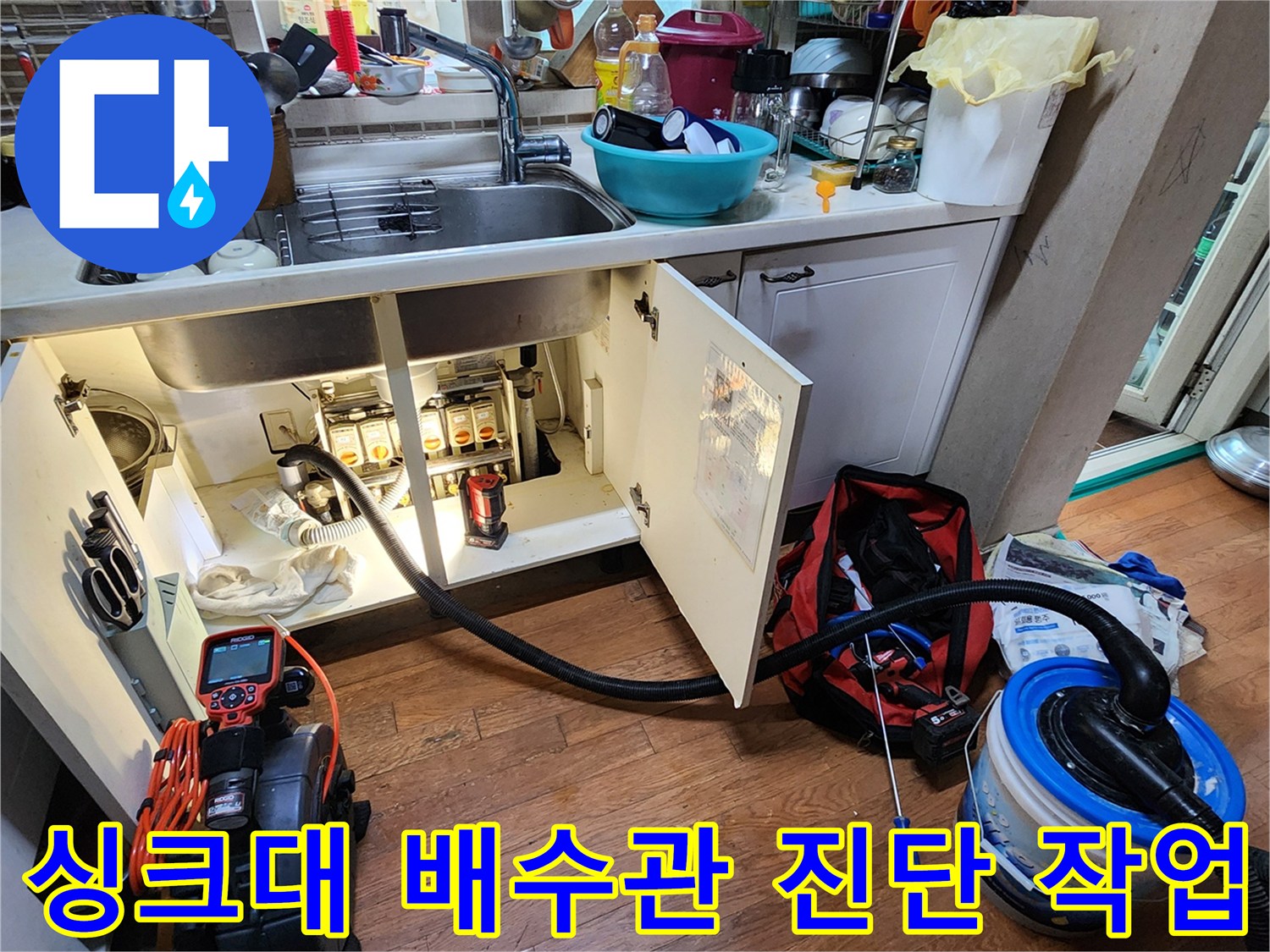 주방 싱크대 하부의 복잡한 배관 구조와 점검 장비 배치 상황