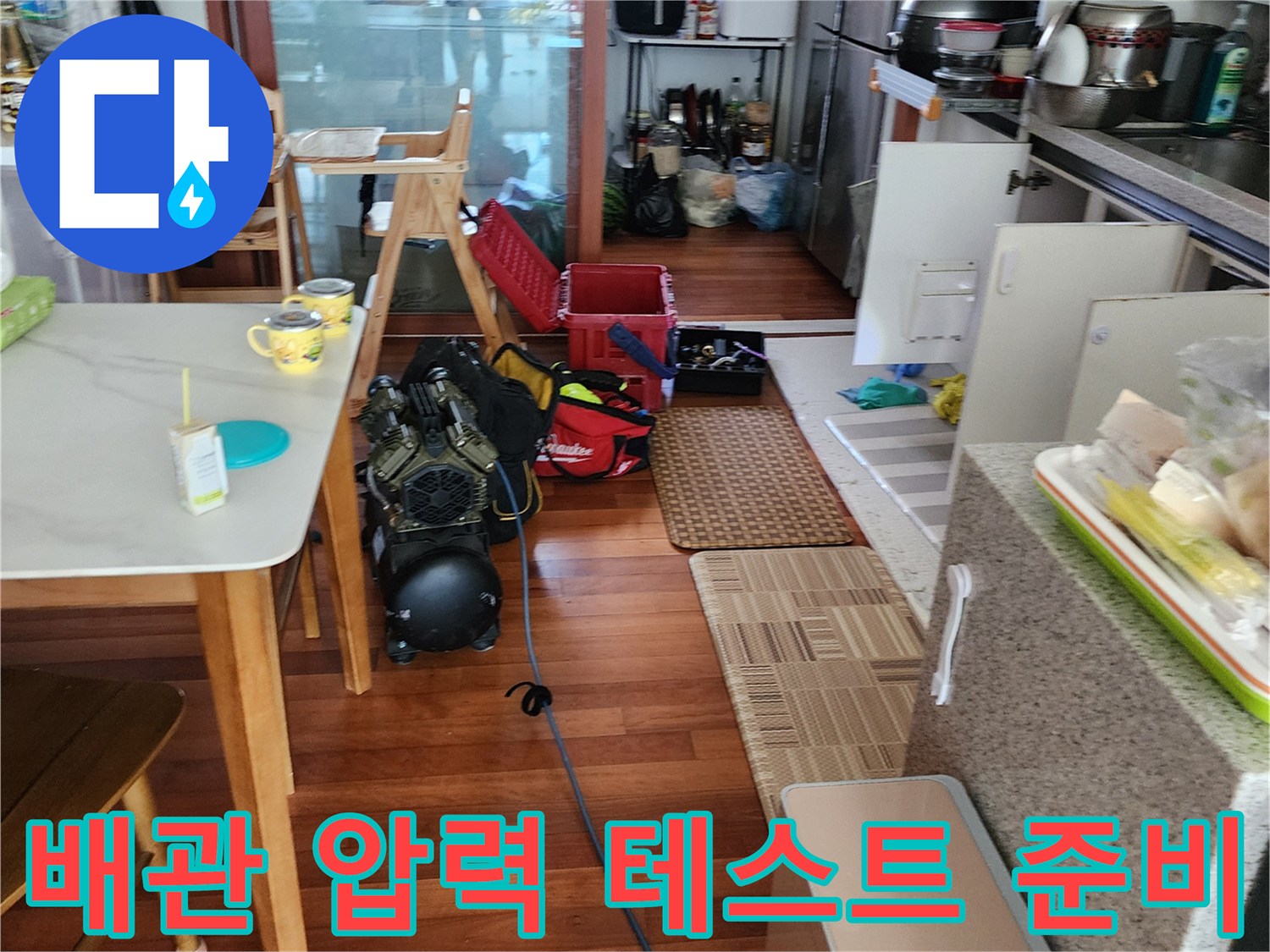 주방 식탁 아래 배치된 누수 탐지용 공압 장비와 배관 연결 호스
