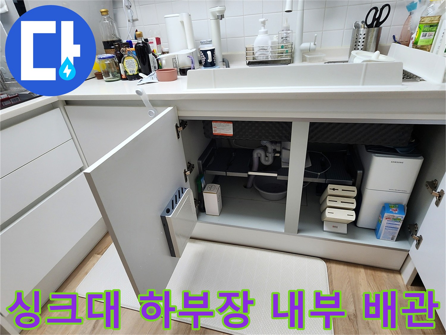 열린 싱크대 문 사이로 보이는 배관과 연결 부위