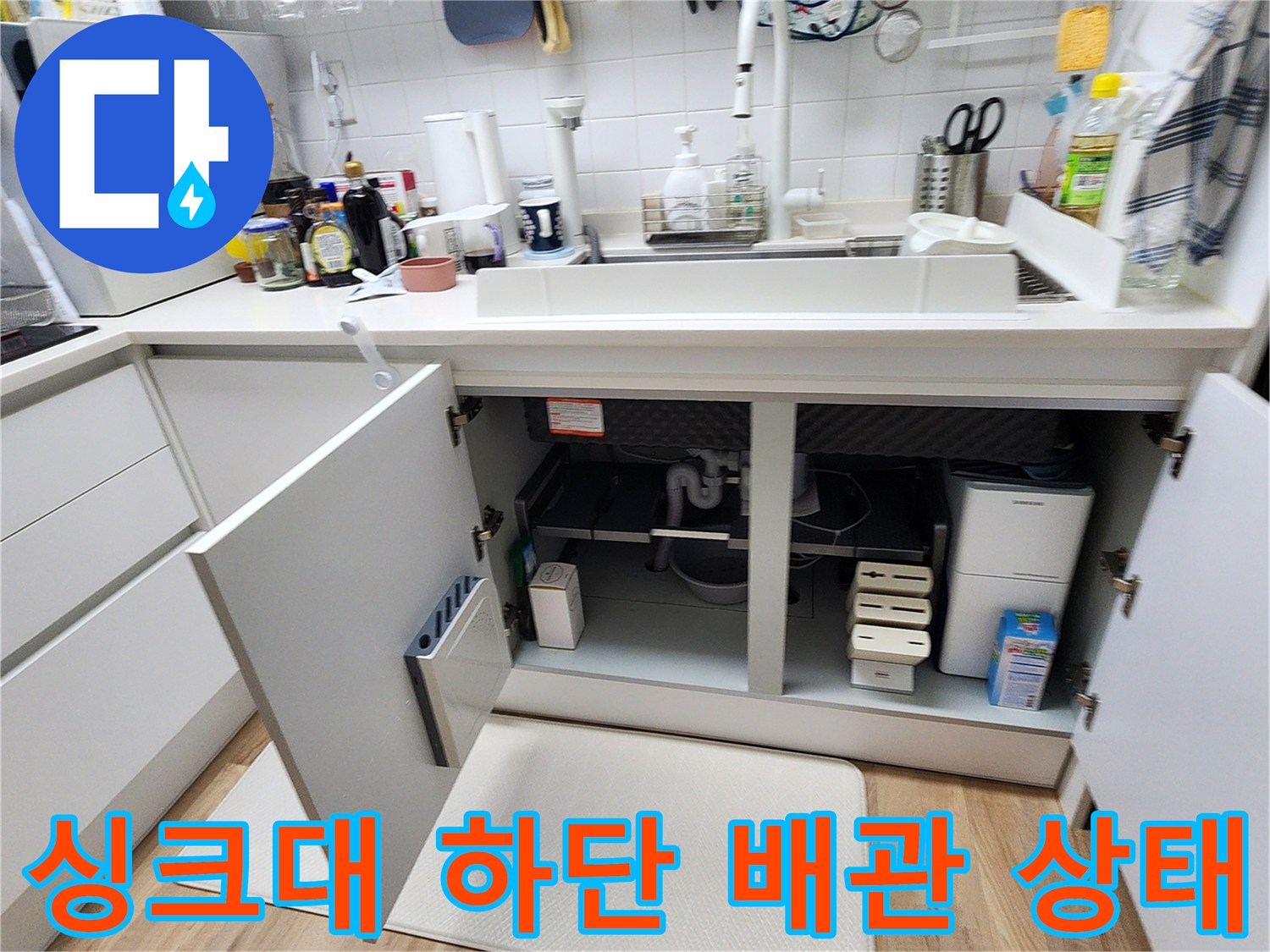 주방 싱크대 아래쪽 배관과 매립함 내부를 근접 촬영한 사진