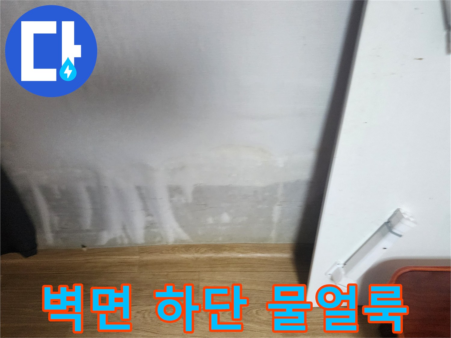 아파트 벽면 하단부에 발생한 심각한 수분 침투와 얼룩 상태입니다.
