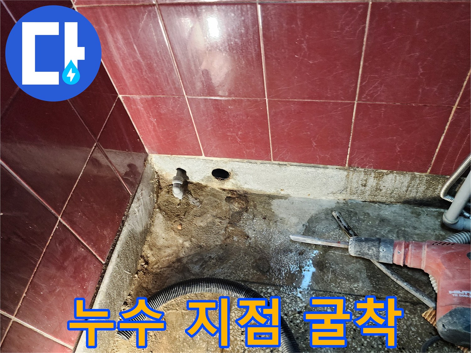 벽면 타일 아래 노출된 배수관 주변의 젖은 흙과 시멘트