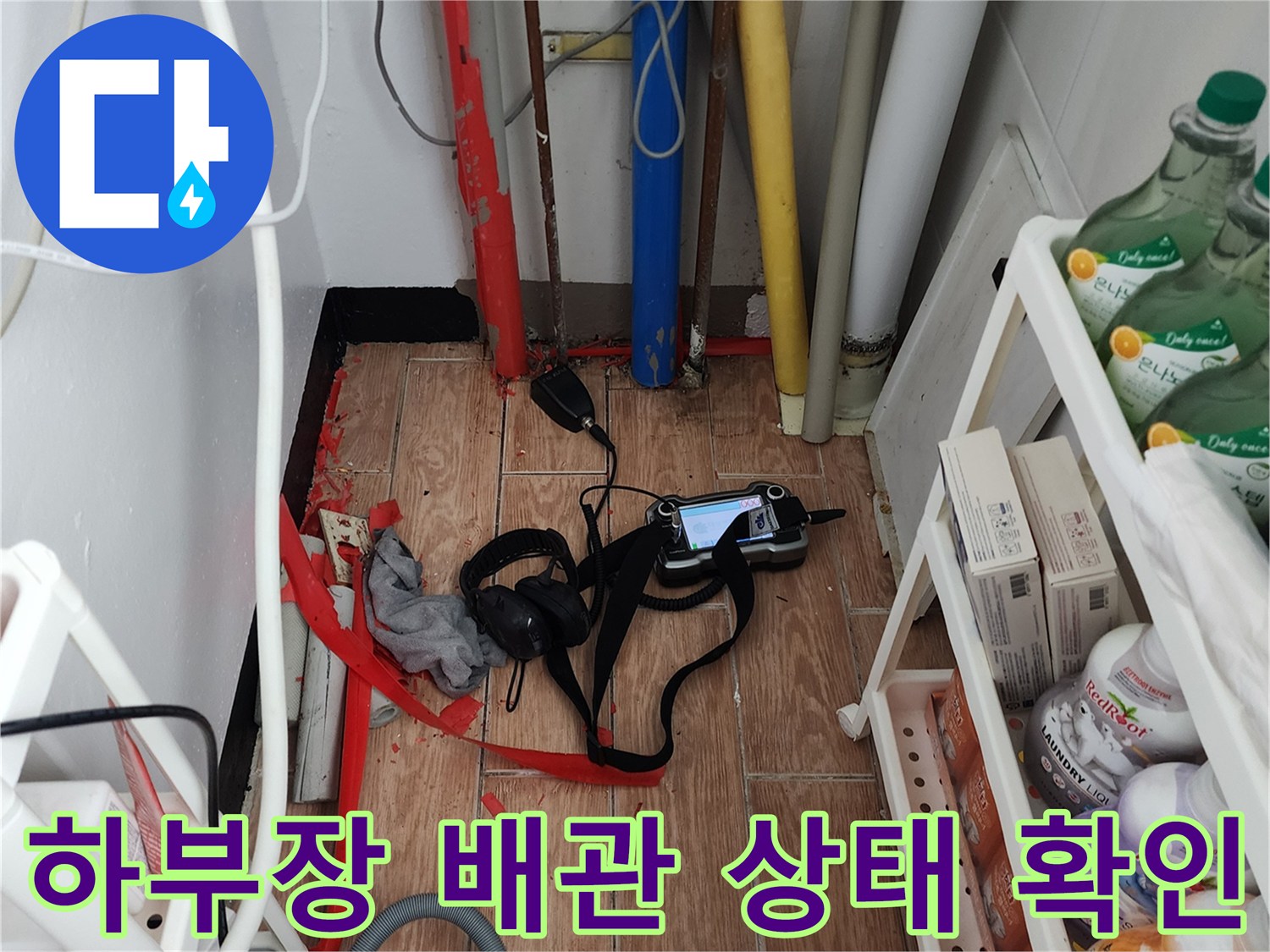 싱크대 아래쪽 배관과 누수 탐지 장비가 놓여 있는 모습