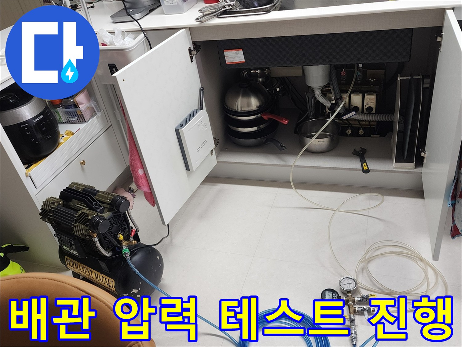 싱크대 하부 배관의 누수 지점을 찾기 위해 공압 장비를 활용하여 정밀 진단을 수행하는 장면입니다.
