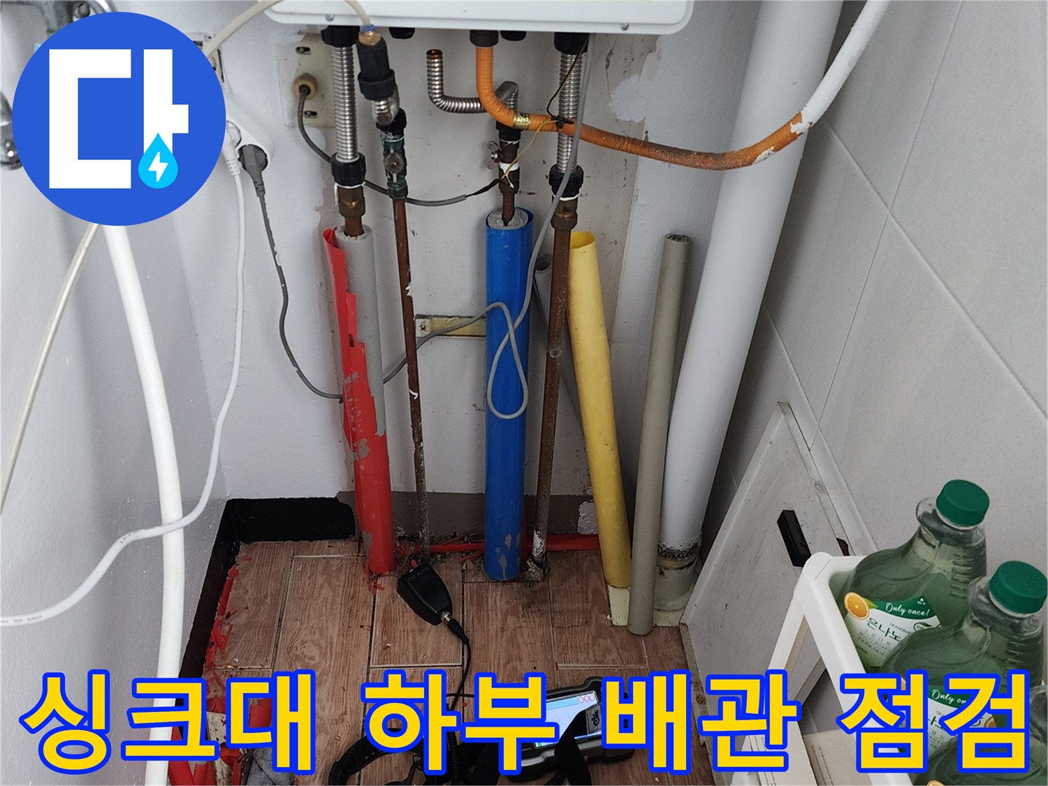 주방 싱크대 아래 복잡한 배관들과 정밀 탐지 장비의 모습