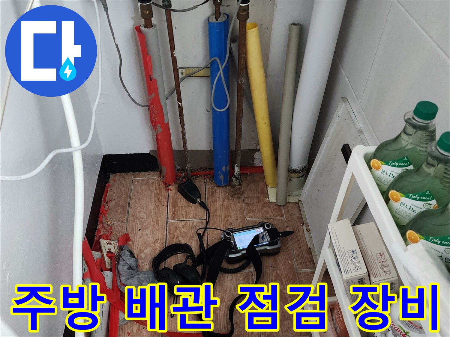 주방 싱크대 하부의 복잡한 배관과 누수 탐지용 디지털 측정기