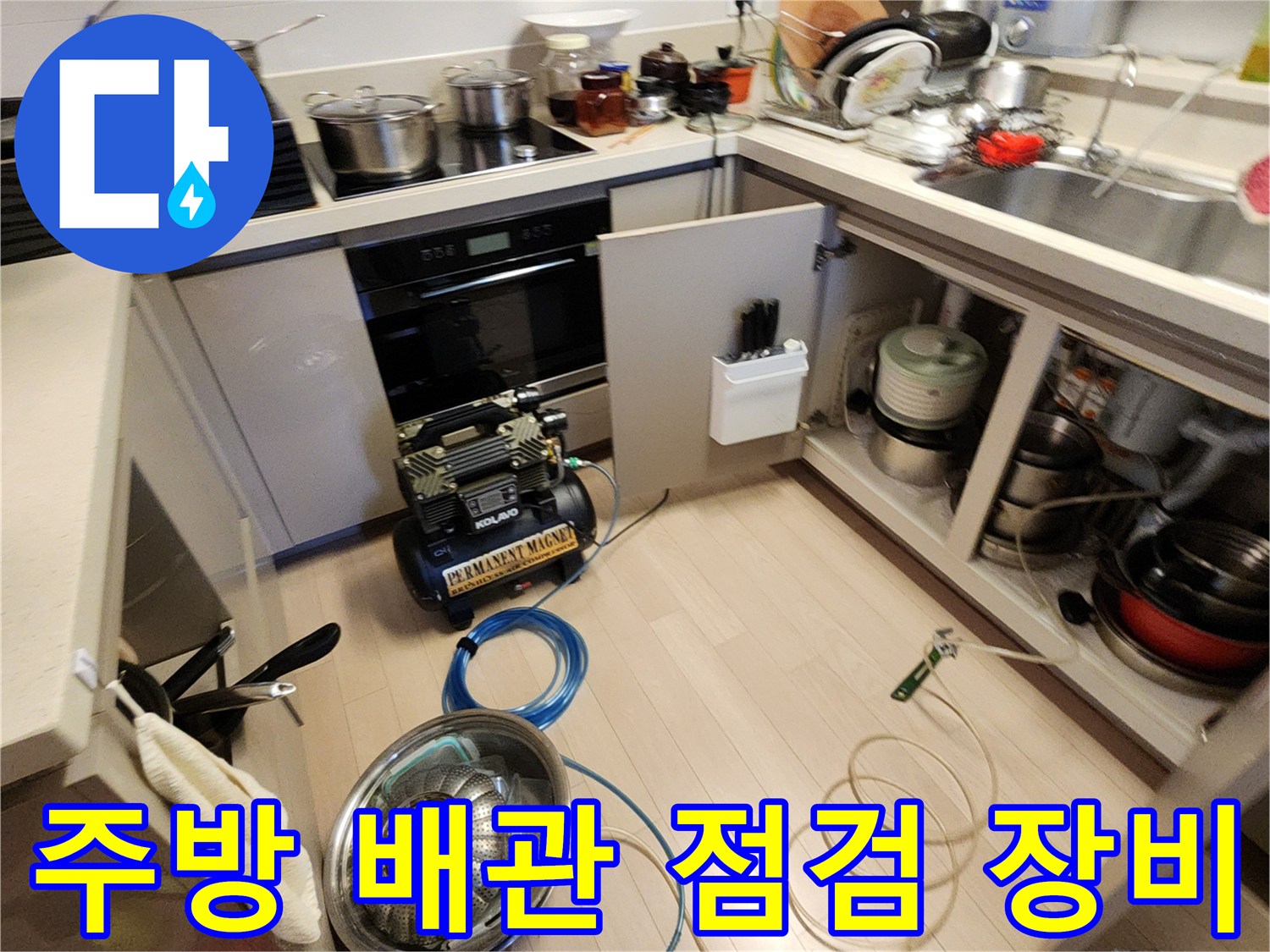 주방 싱크대 하부 공간에 배치된 공기압 테스트 장비와 호스