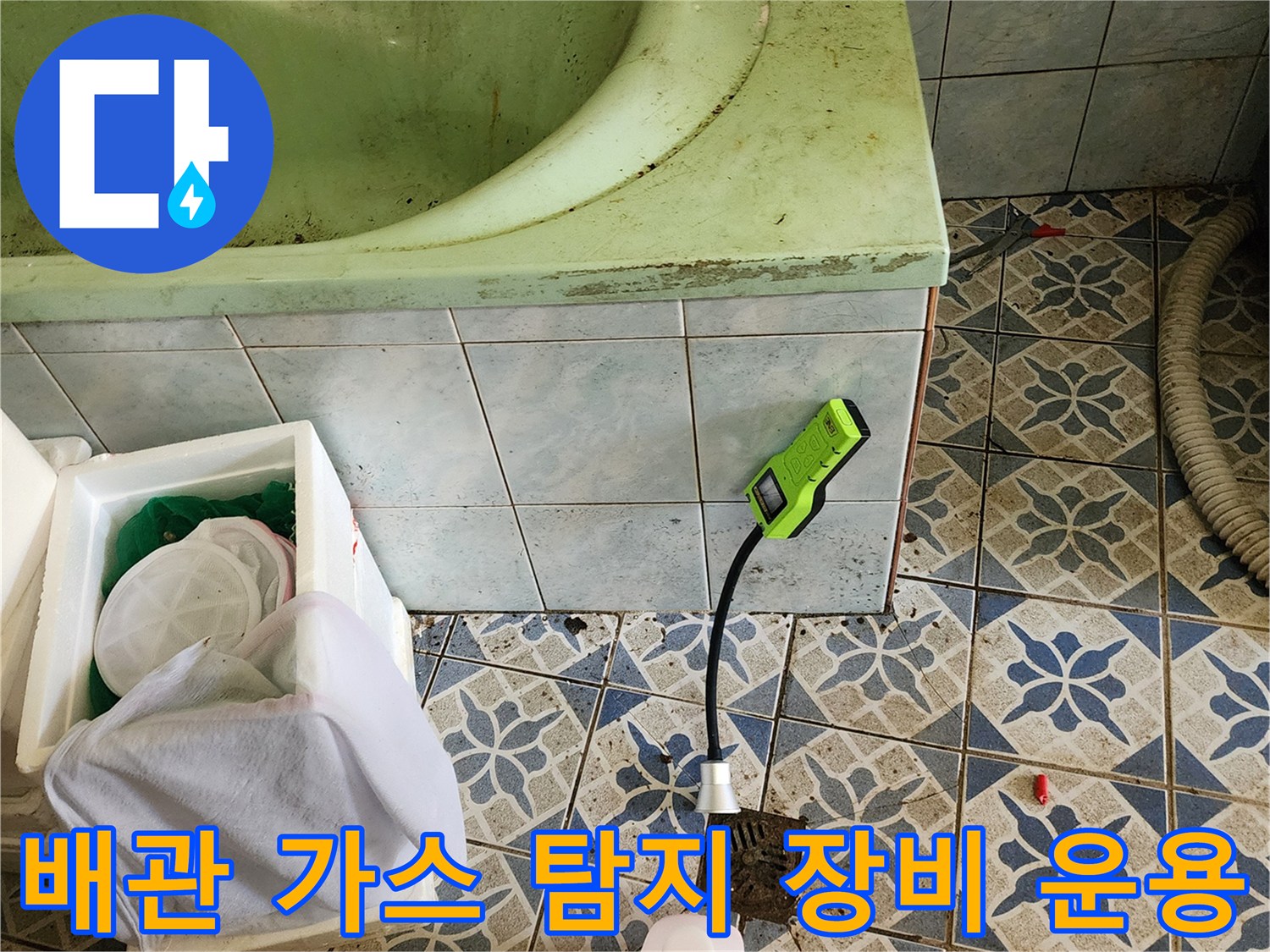 초록색 가스 탐지기를 바닥 타일 근처에 배치하여 배관 누수를 추적하는 장면