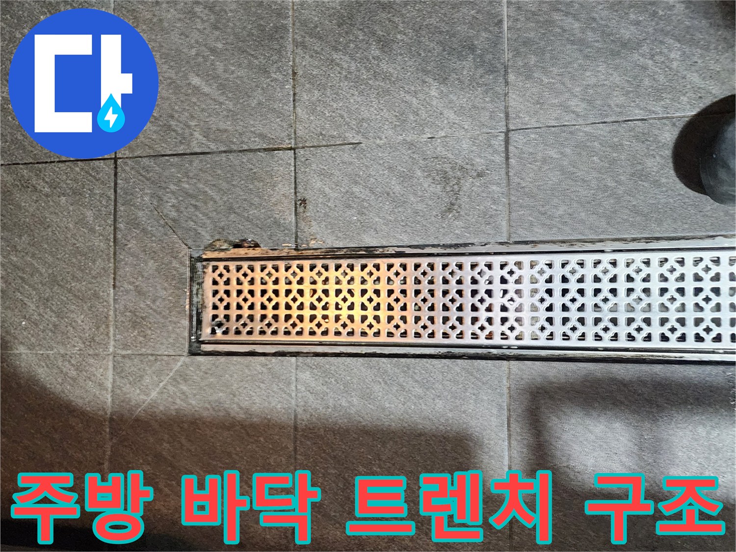 어두운 회색 타일과 금속제 배수 트렌치의 접합부
