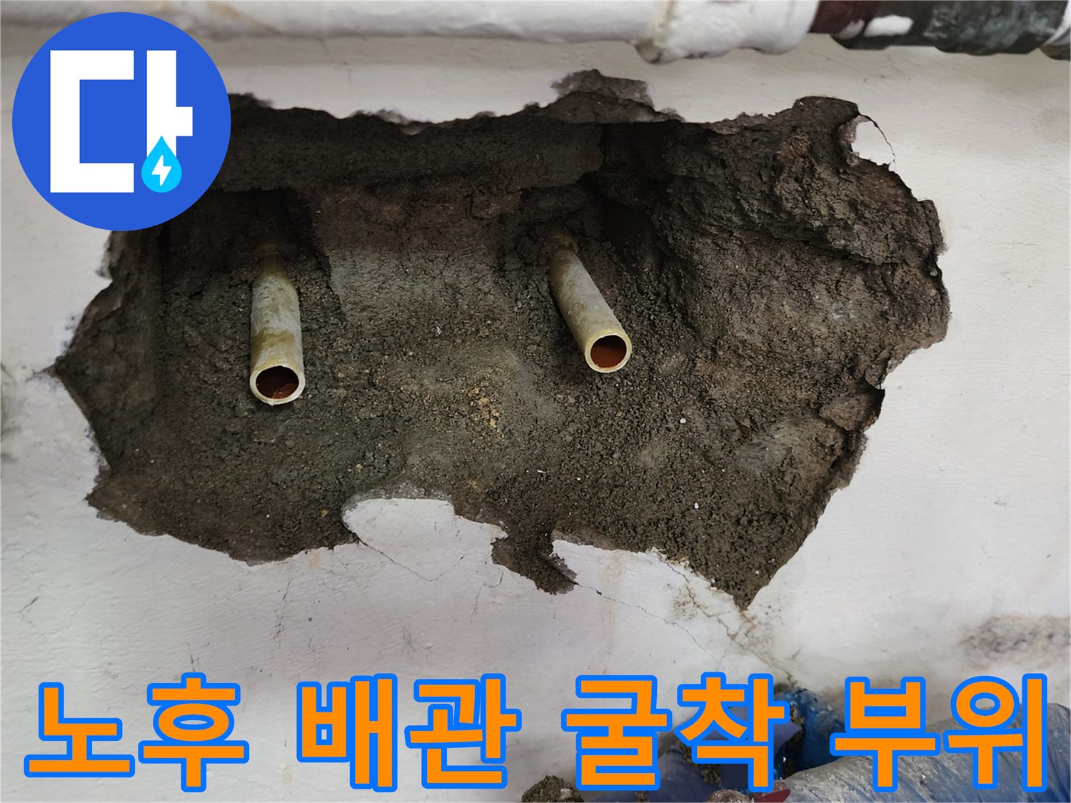 벽면을 굴착하여 드러난 노후된 급수 배관과 젖은 시멘트층