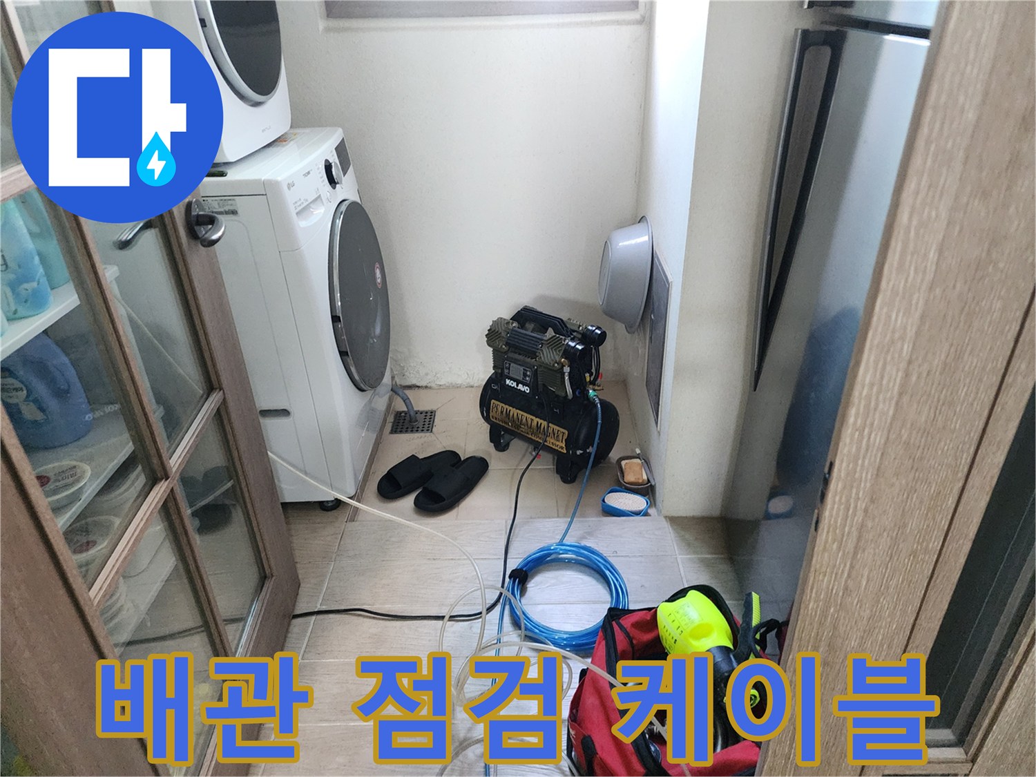 세탁기 옆 바닥에 놓인 검은색 탐지 장치와 파란색 전선