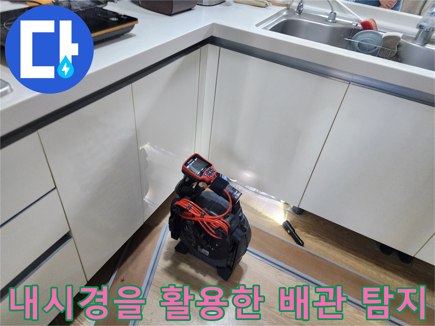 싱크대 하단 배관 내부 상태를 점검하기 위해 내시기 카메라를 사용하는 장면