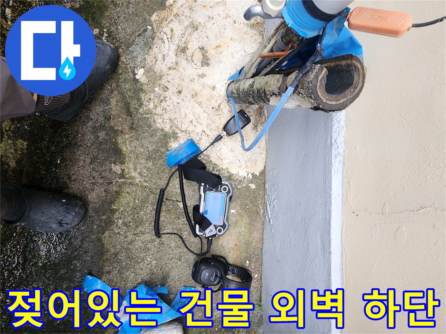 배관 주변의 누수로 인해 젖은 지면과 노출된 배관 부속