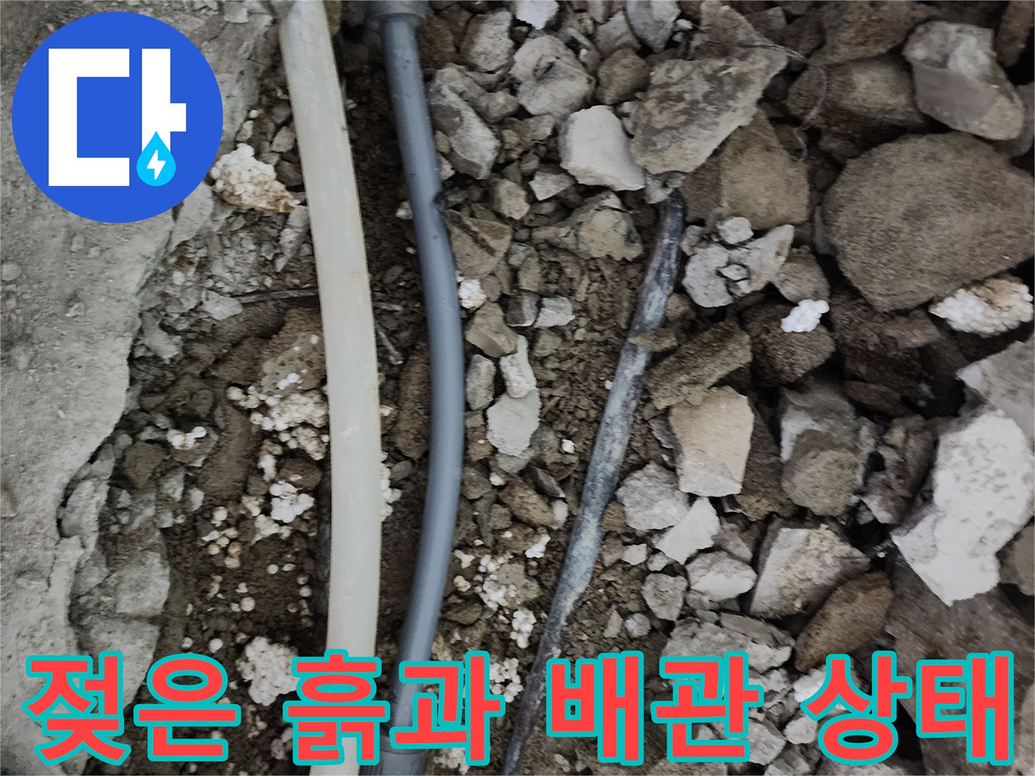 매립 배관 주위의 젖은 흙과 깨진 콘크리트 파편