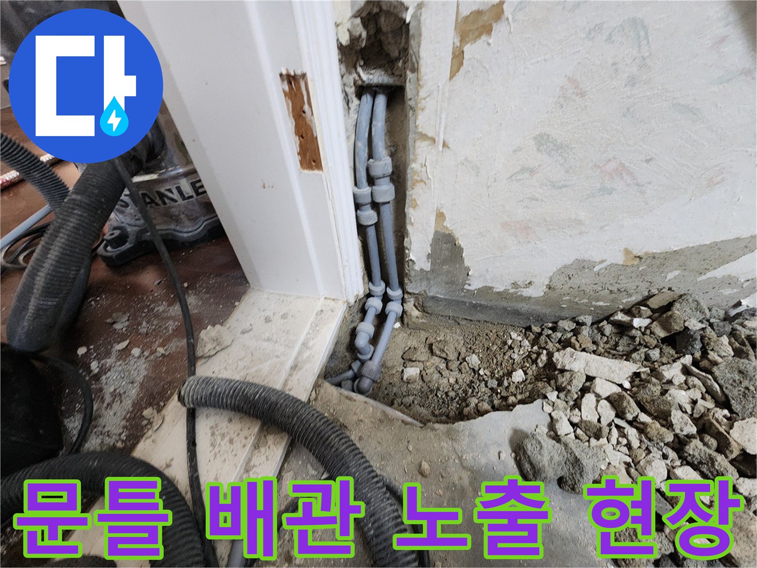 문틀 하단 굴착된 부위에 노출된 회색 배관과 연결 부속 모습