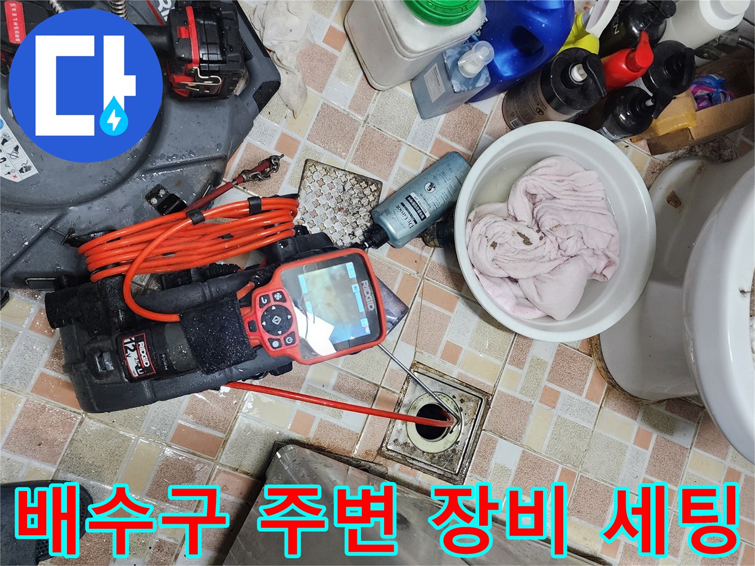 욕실 배수구 근처에 배치된 리지드 탐지 장비와 청소 도구들