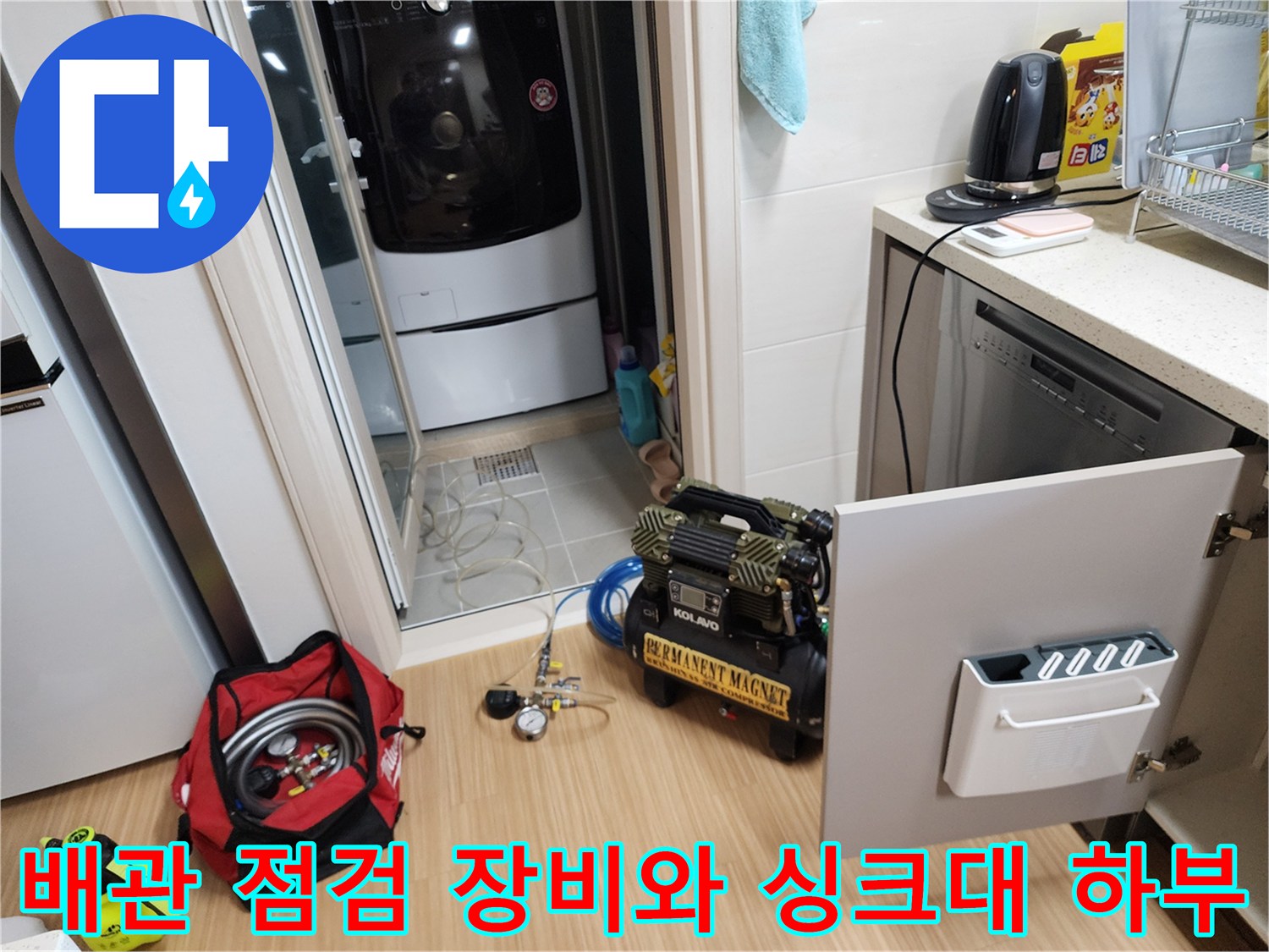 싱크대 하부장 옆에 배치된 배관 세척용 컴프레셔와 작업 도구들