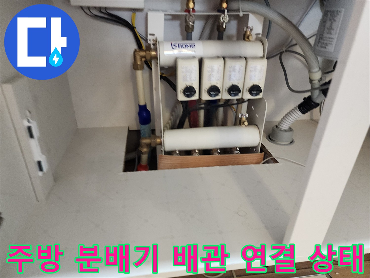 싱크대 하부장 내부에 노출된 수도 분배기와 연결 배관의 모습입니다.