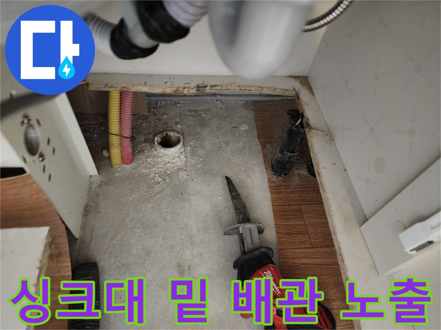 하부장 아래 굴착된 바닥에 드러난 배관과 작업용 전동 공구입니다.