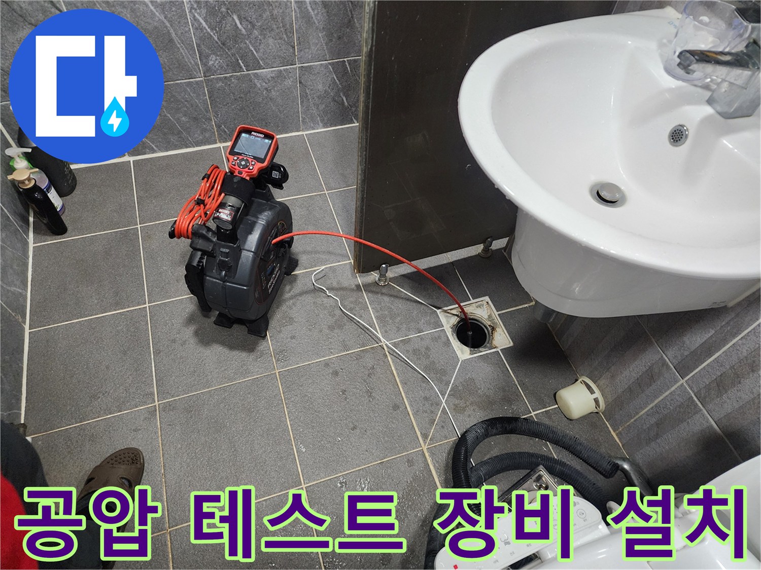 세면대 아래 화장실 바닥 배수구에 연결된 누수 탐지용 공압 장비