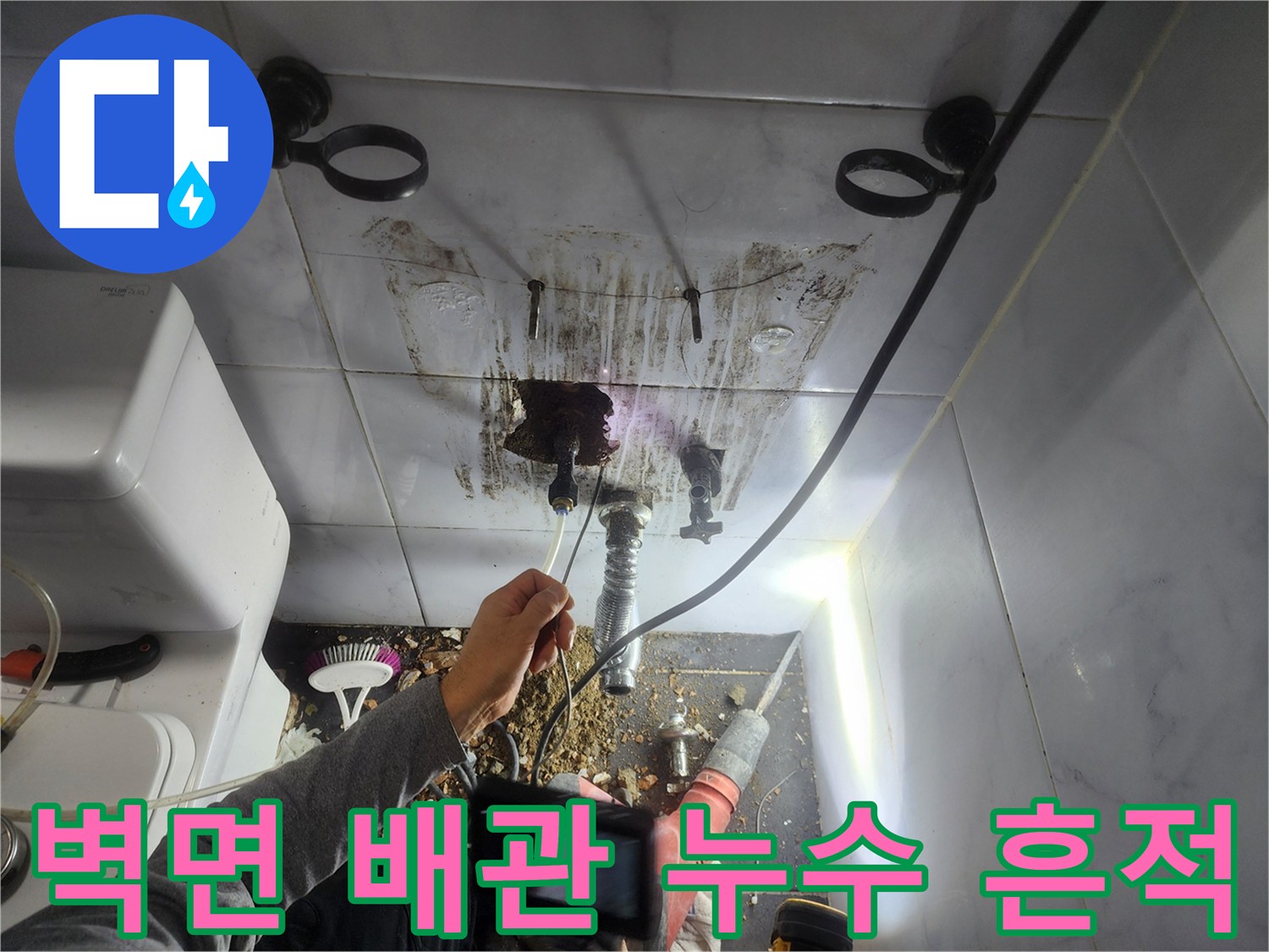 배관 연결 부위 주변의 젖은 타일과 오염된 벽면 상태