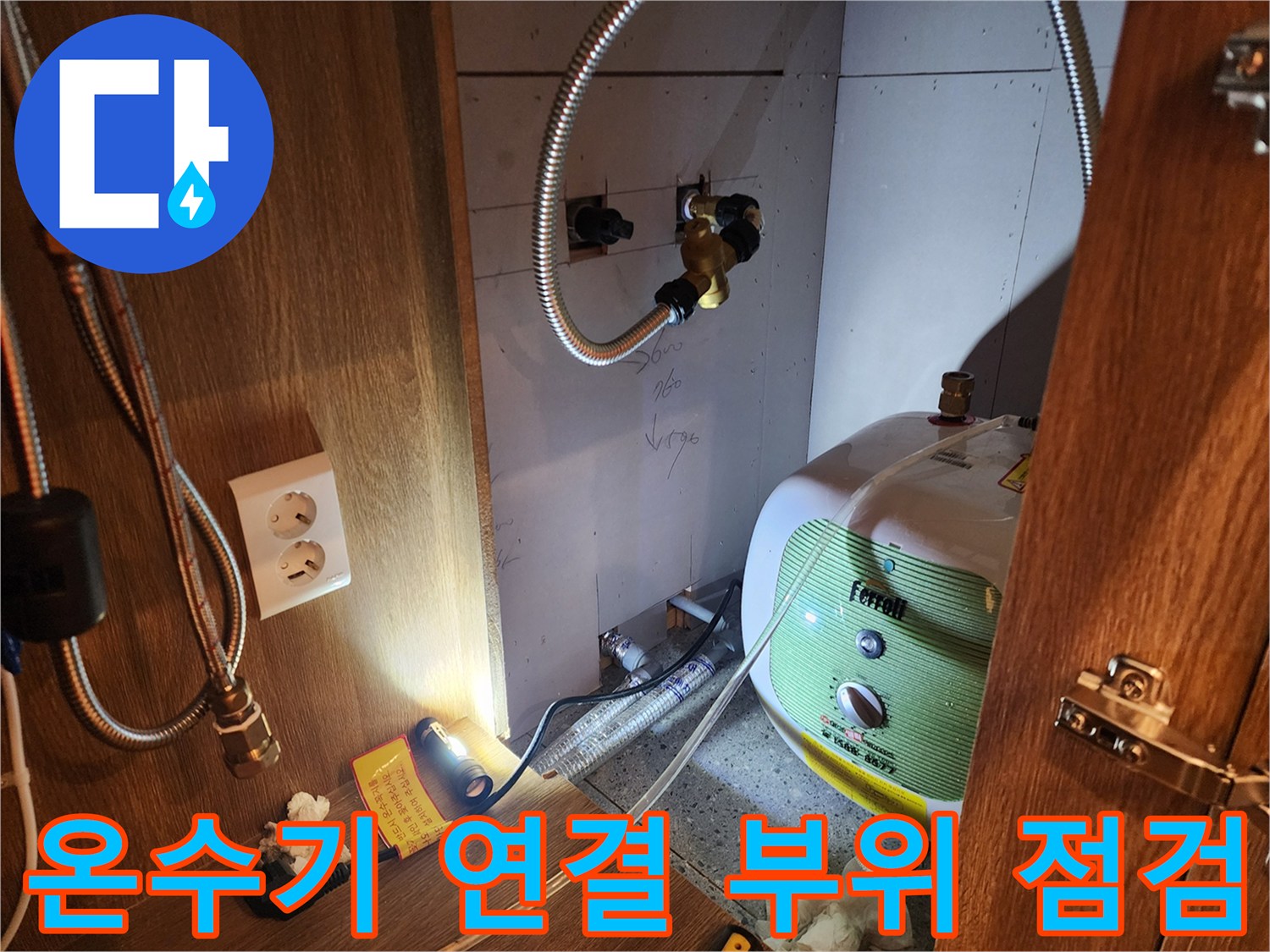 금속 재질의 플렉시블 호스와 전기 온수기 본체의 연결 상태를 근접 촬영한 사진