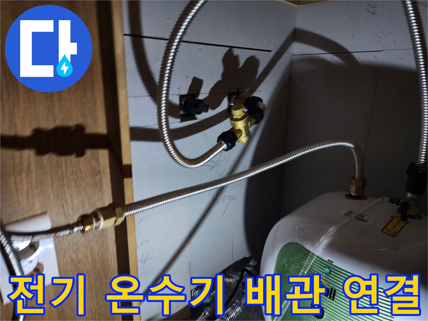 주방 싱크대 아래 설치된 전기 온수기와 급수 호스