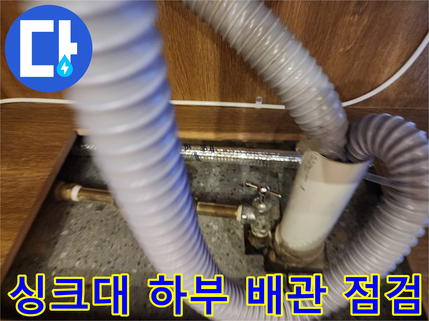 주방 싱크대 아래쪽의 온수기 연결 호스와 밸브 부위 상세 모습-
