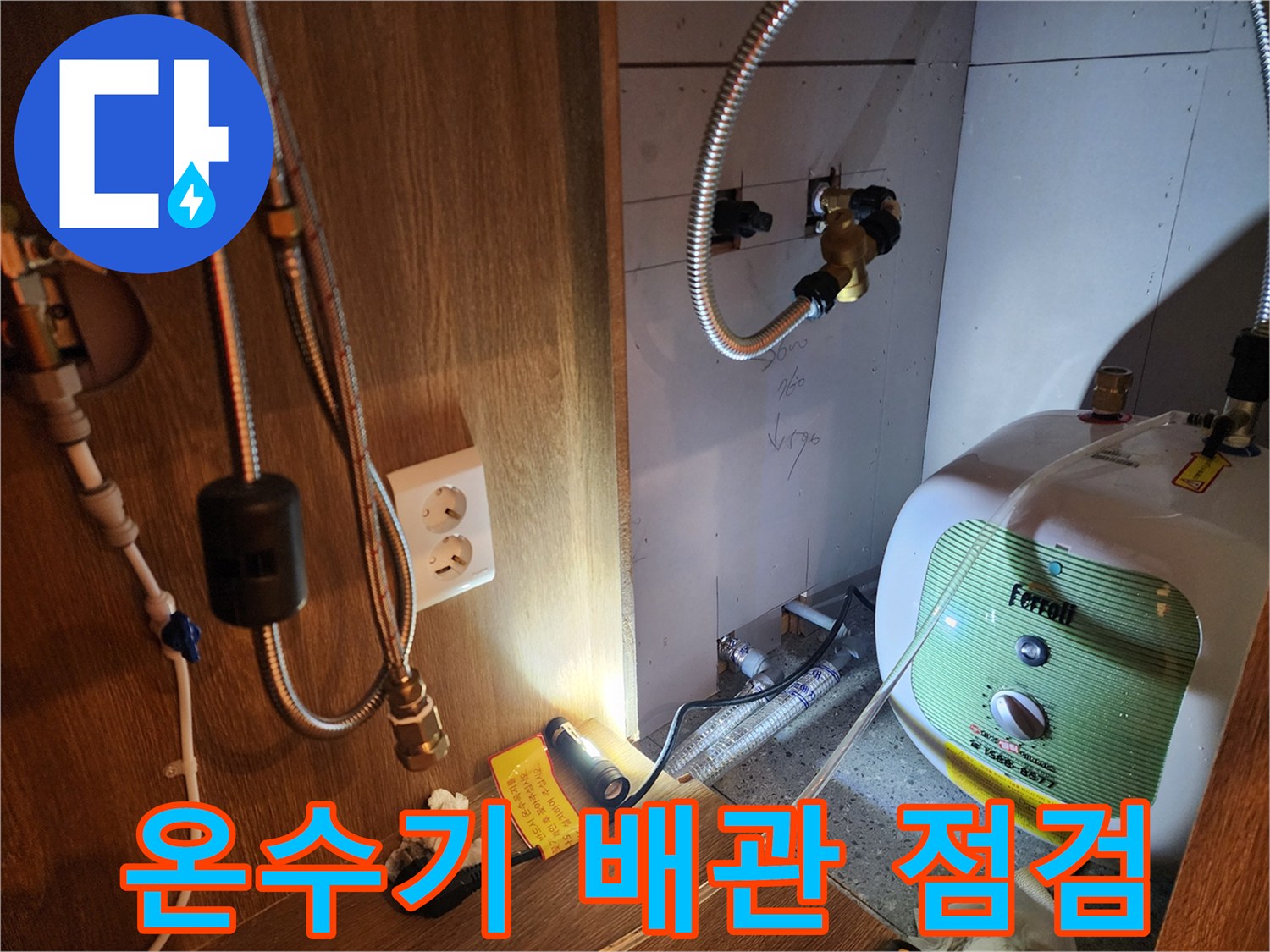 주방 싱크대 하부장 내 설치된 전기 온수기와 연결 배관 상태 사진