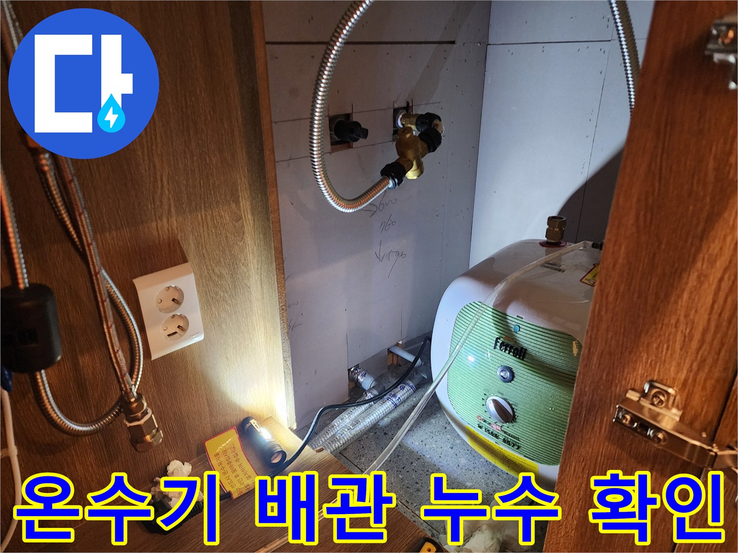 주방 하부장 내부-전기 온수기와 연결된 금속 호스 부위 점검 중