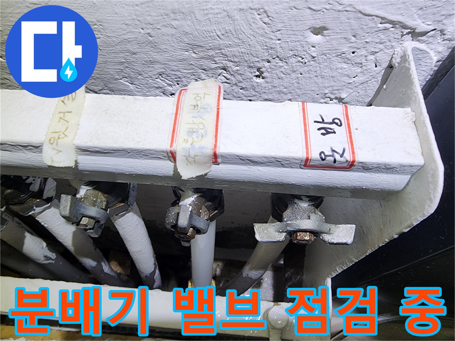 금속 재질의 보일러 분배기 밸브와 연결된 하얀색 배관들