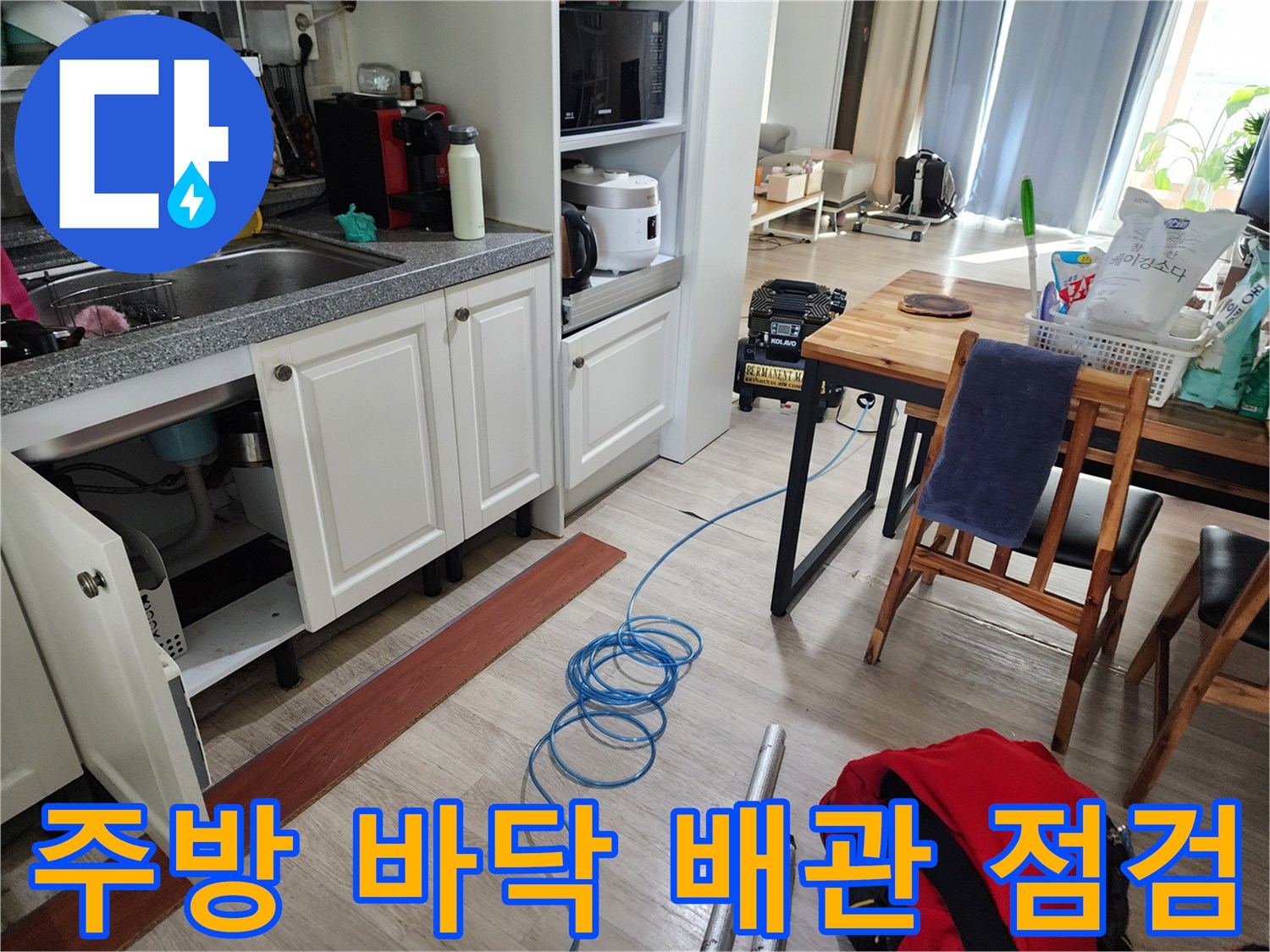 싱크대 하부장 근처 바닥에 놓인 누수 탐지용 가스 호스와 장비들
