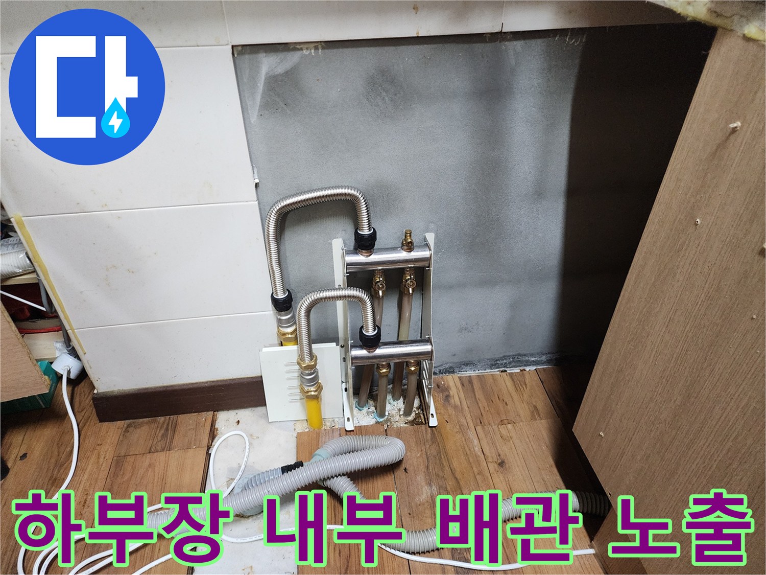 싱크대 밑 분배기와 연결된 은색 주름관-누수 지점 탐지를 위한 점검 장면입니다.