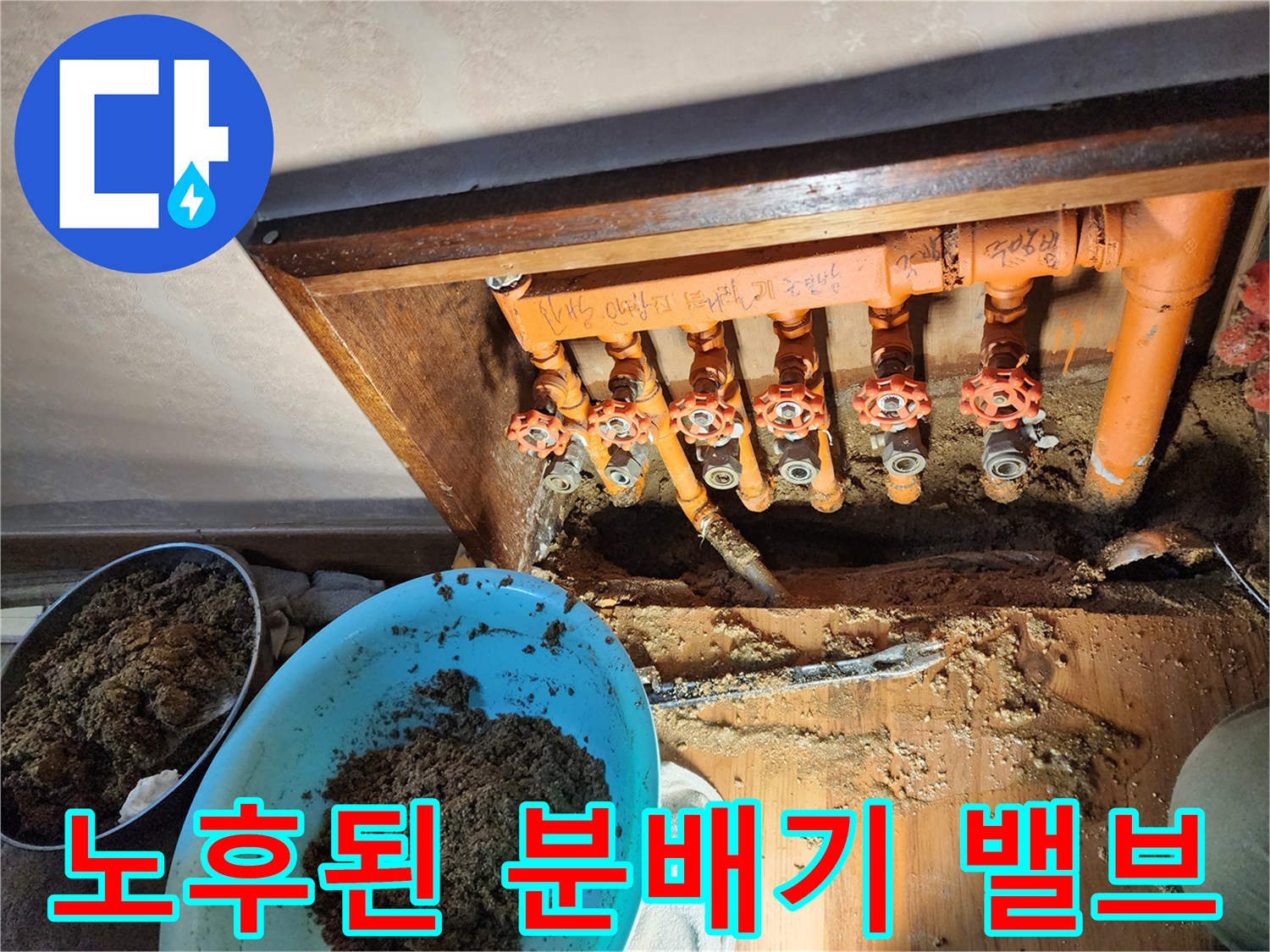 오렌지색 보온재가 입혀진-노후된 난방 분배기와 밸브 연결부