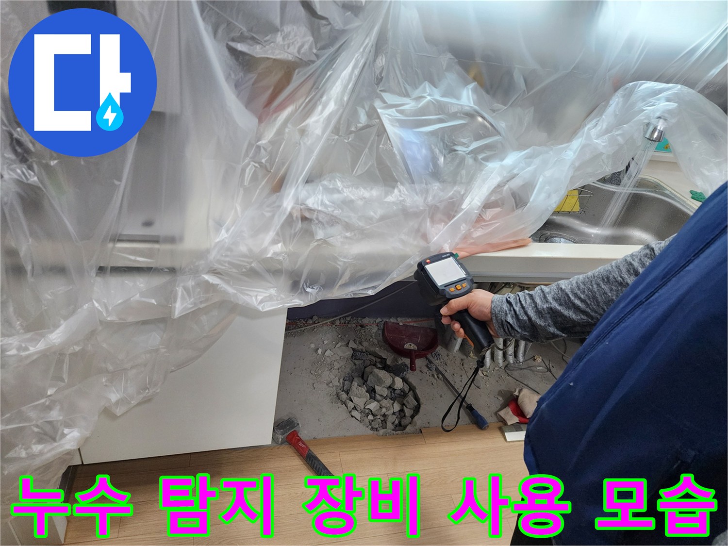 싱크대 아래 공간에서 가스 탐지기로 배관을 점검하는 엔지니어의 손