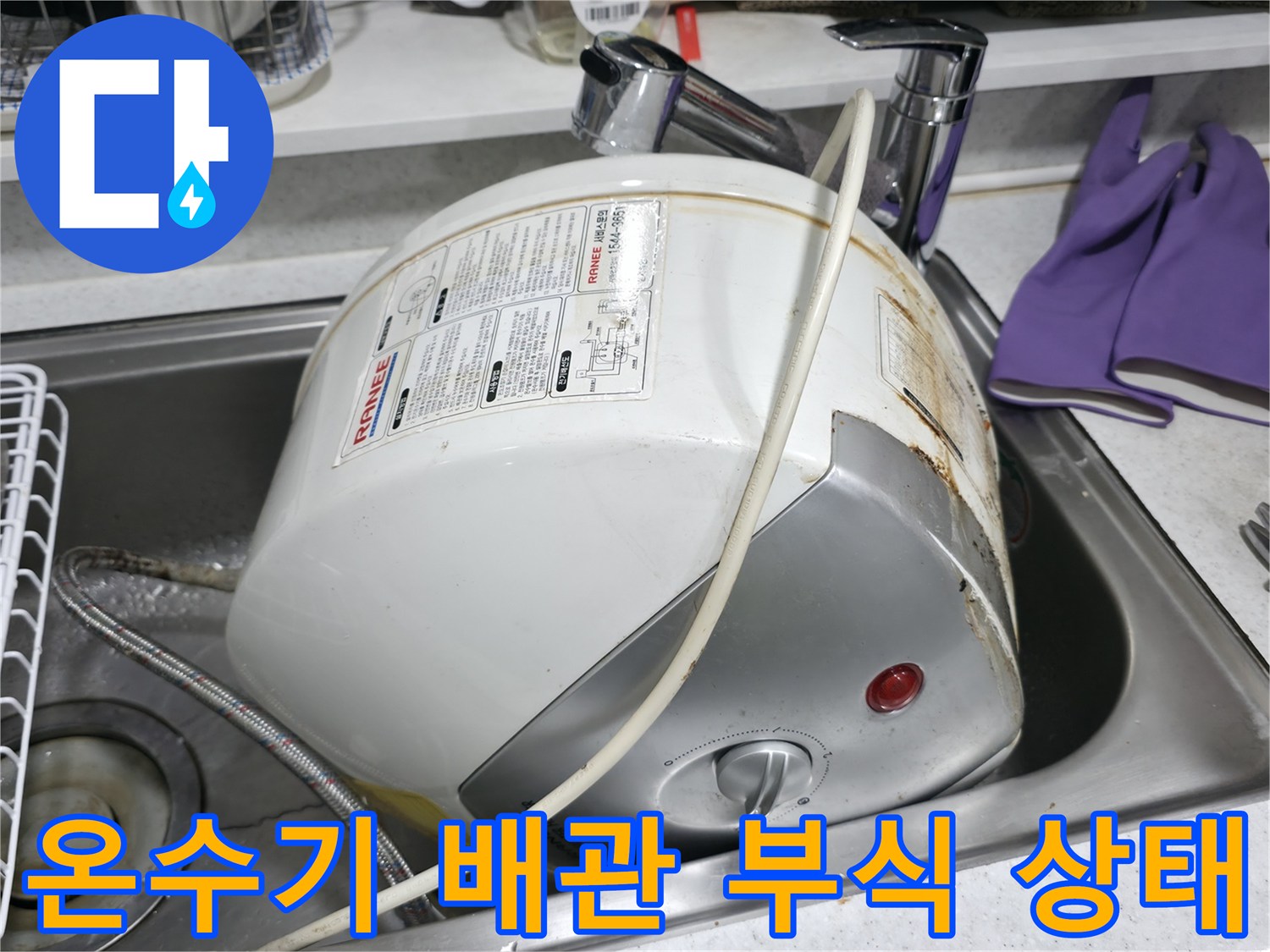 싱크대 아래 설치된 소형 전기 온수기의 배관 연결 부위 부식 및 누수 흔적