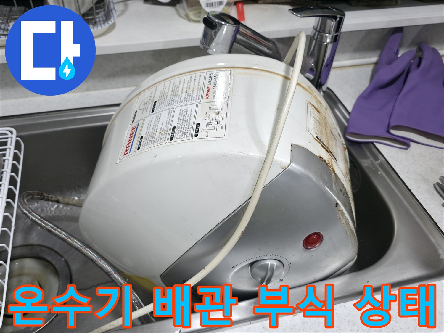 싱크대 하단-노후된 전기 온수기 본체와 부식된 연결 부위 모습