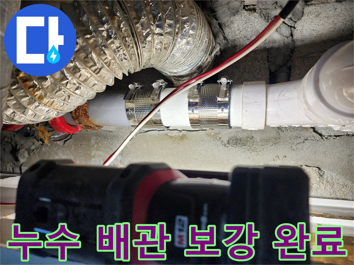 금속 밴드로 조여진 PVC 배관과 주변 단열재 모습입니다.