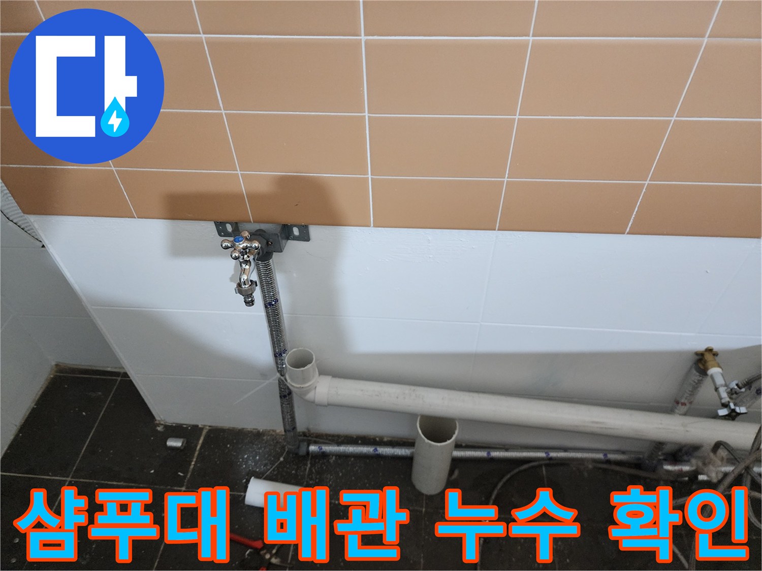 벽면 타일 아래로 연결된 수직 급수관과 가로 배관의 교차점