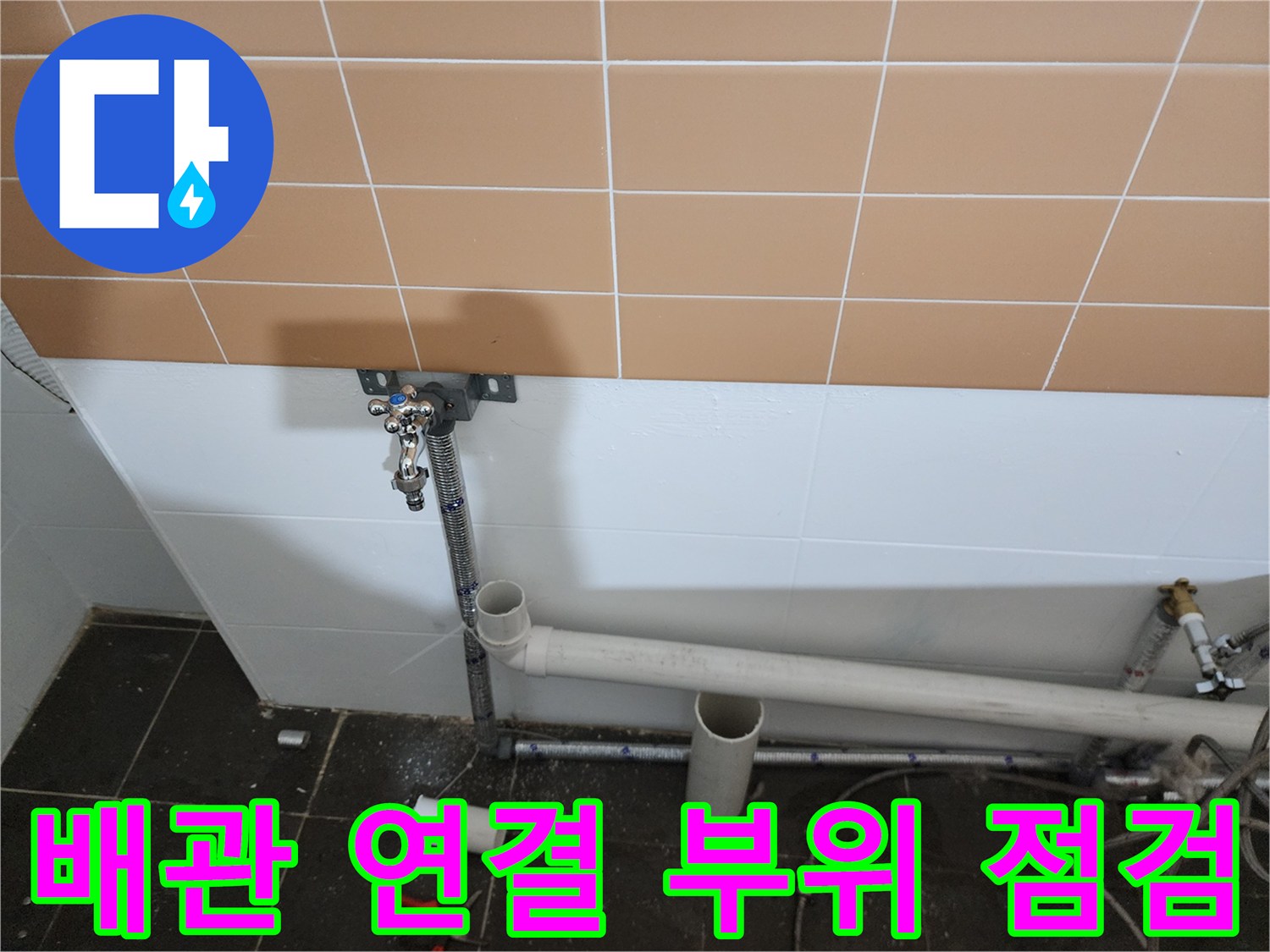 타일 벽면에 설치된 수전과 배관의 연결 상태를 촬영한 사진입니다.