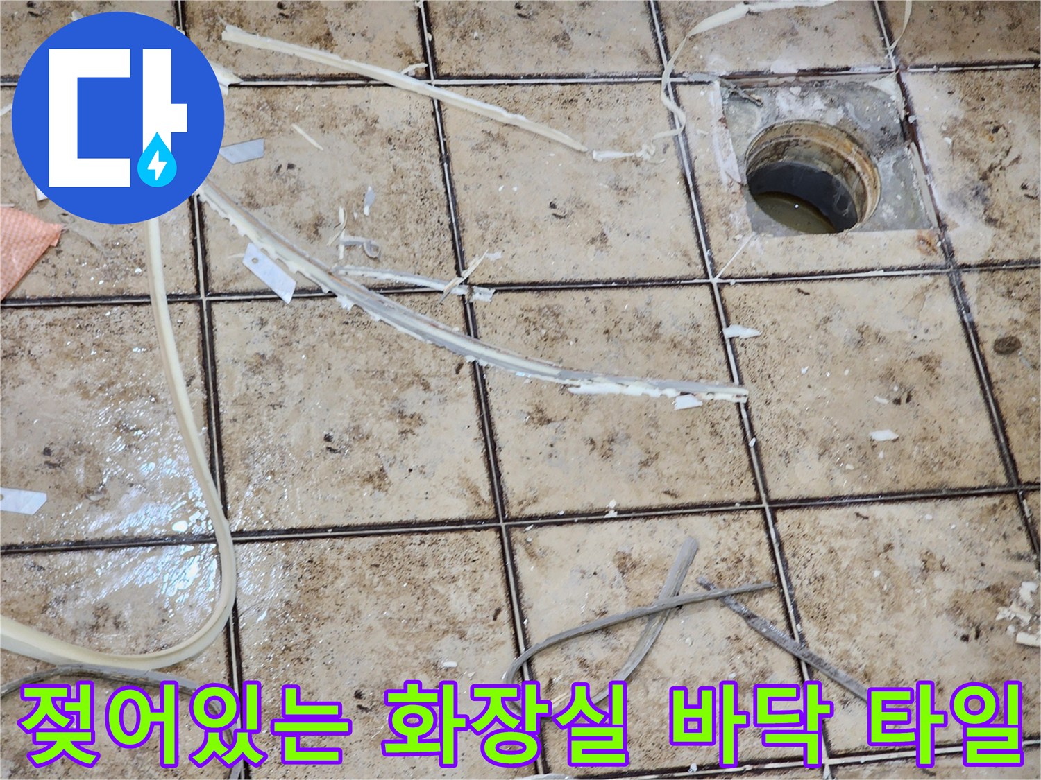 배수구 주변의 젖은 타일과 탈락된 조각들을 보여주는 이미지입니다.