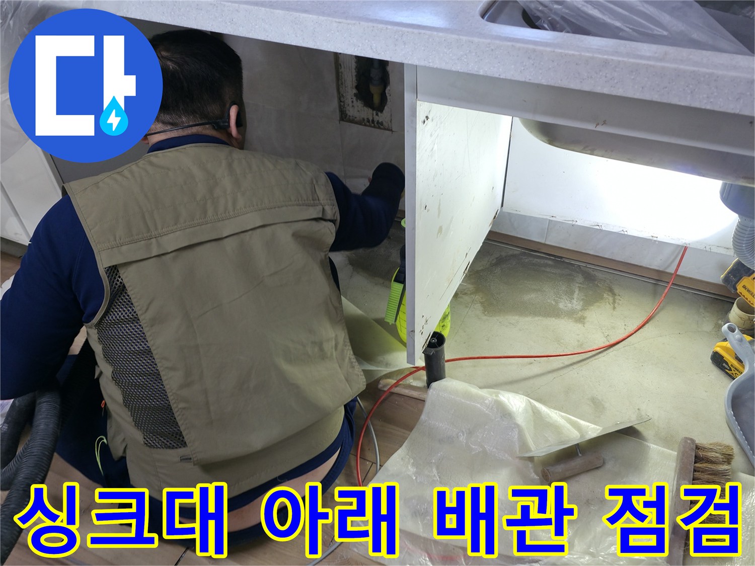 싱크대 하부장 공간에서 배관 상태를 관찰하는 엔지니어의 모습입니다.