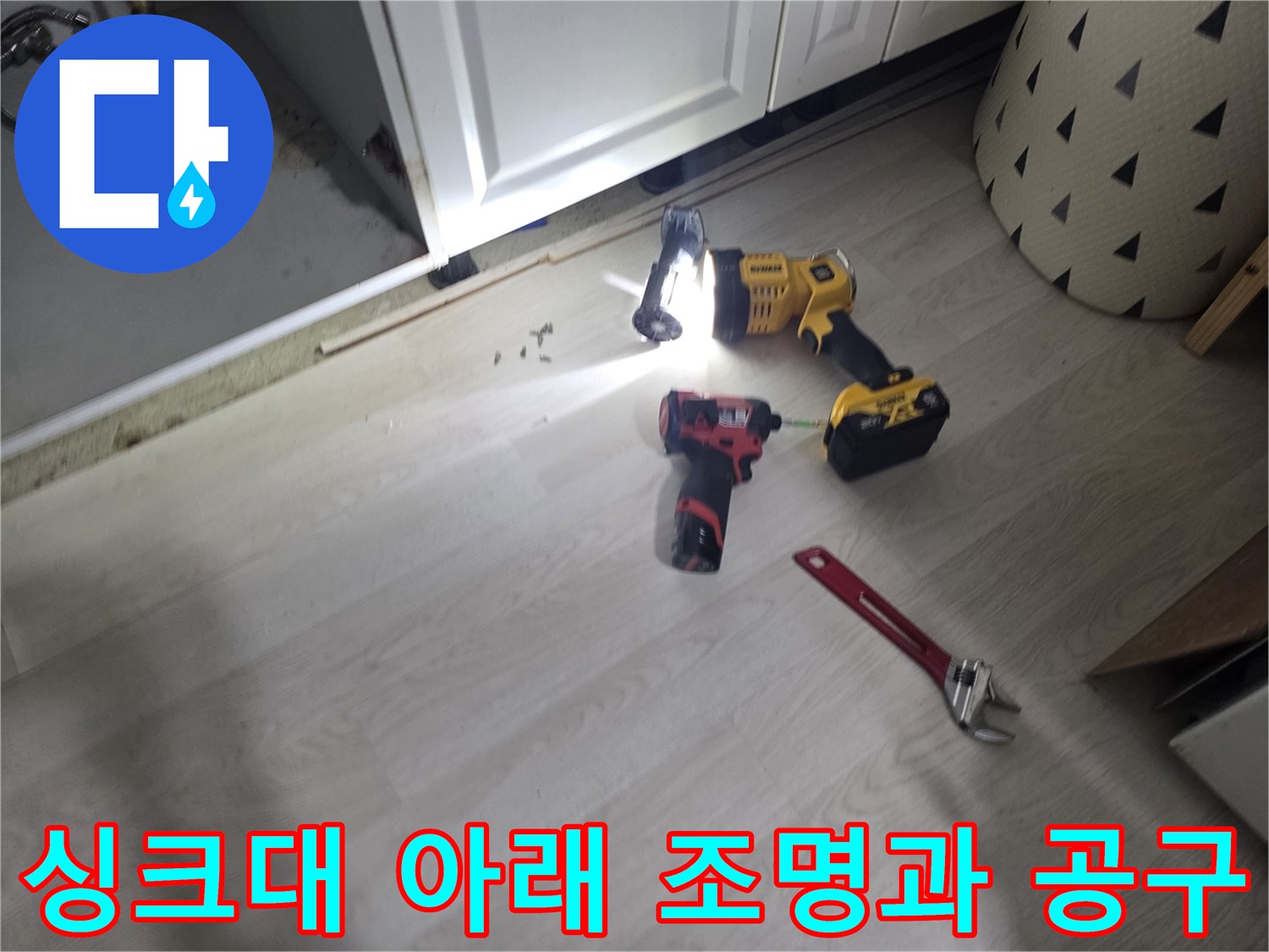 어두운 싱크대 밑을 밝히는 랜턴과 렌치 배치